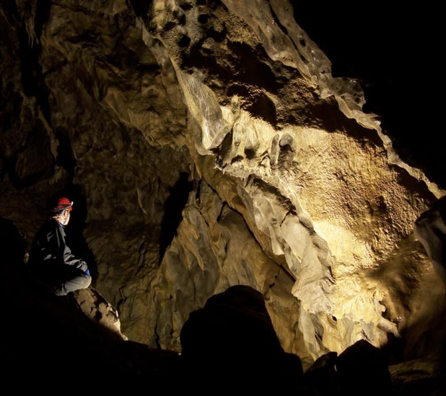 A man looking at the formations in Canmore Cave