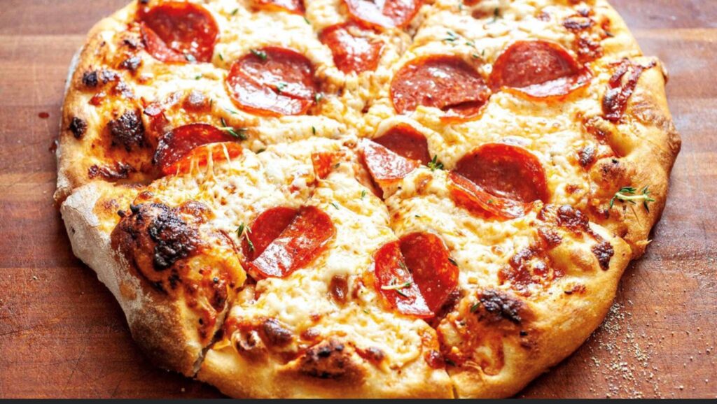 A hot cheese and pepperoni pizza, cut into eight slices on a wooden platter.  The dining special at Mineshaft Tavern in Canmore, Alberta