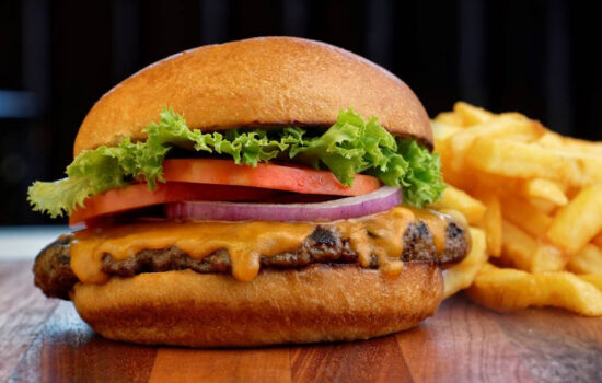 Juicy burger topped with lettuce, tomato, red onions and cheese with a side of fries.  Served at Fergus & Bix as their Thursday dining special in Canmore, Alberta