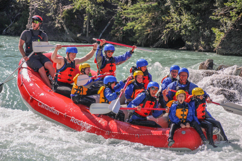 Rafters of all ages rafting down the Kananaskis River in a red raft.
