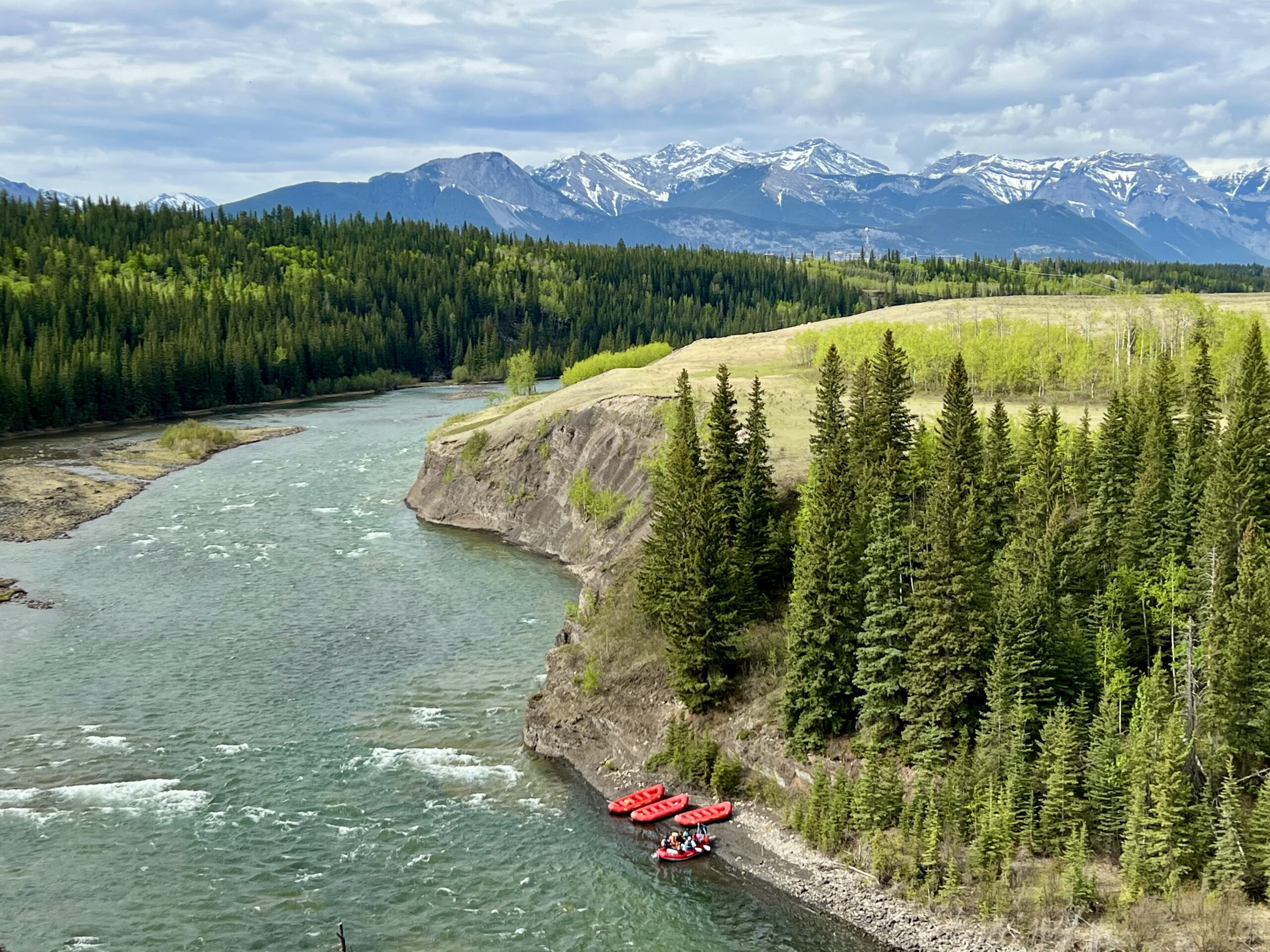 Snowcapped Mountains and lush green space on the river with Canadian Rockies Rafting