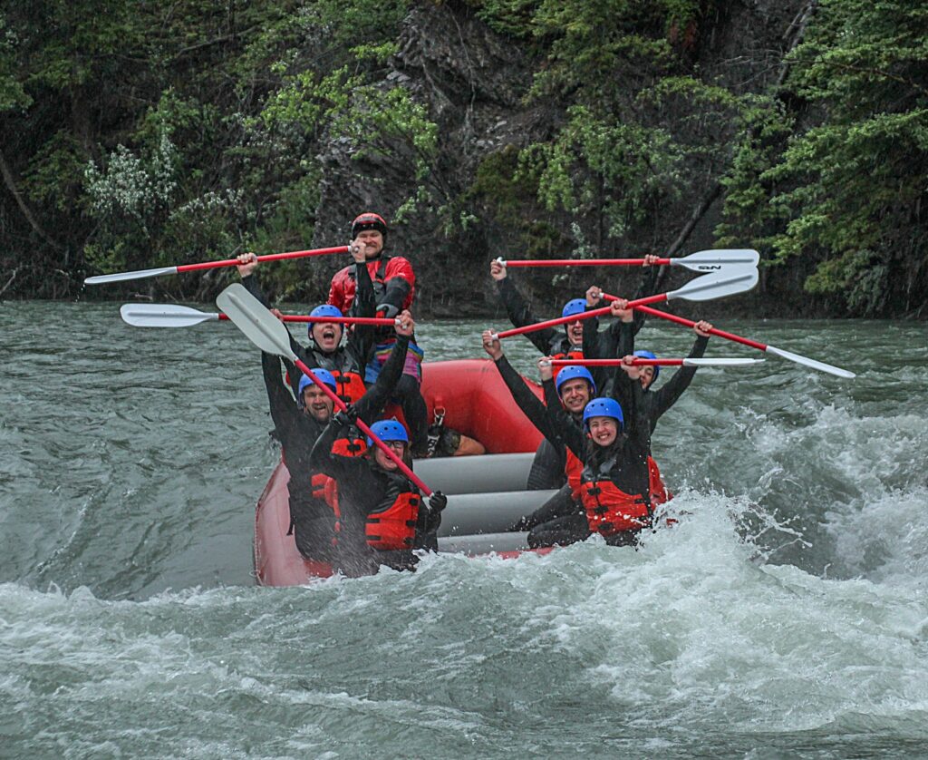 Rafters in red raft rafting a class 3 rapid with Canadian Rockies Rafting - rafting in the rain