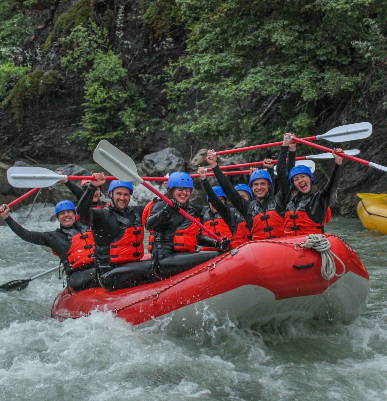Red Raft with happy rafters rafting in the rain with Canadian Rockies Rafting